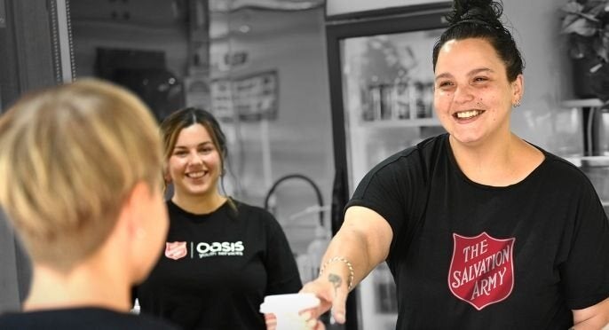 Smiling Salvos worker hands someone a coffee