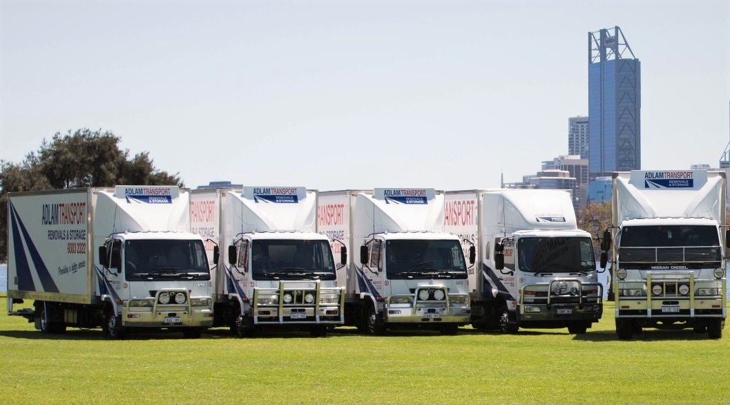 Five Adlam removalist trucks in a line