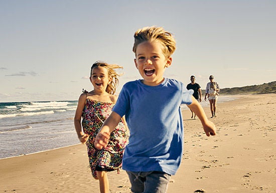 Two children running along the beach laughing