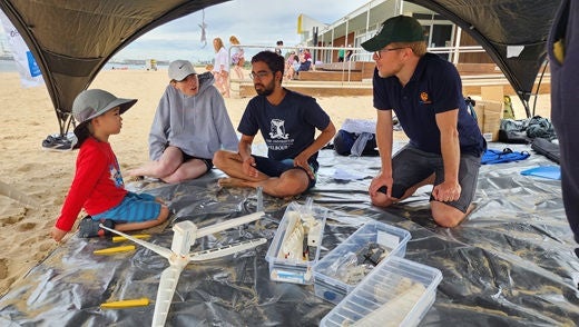 A young child, two Melbourne University volunteers and Alinta Energy Project Development Manager Linden Blair collaborate on a miniature wind turbine build at Port Melbourne.