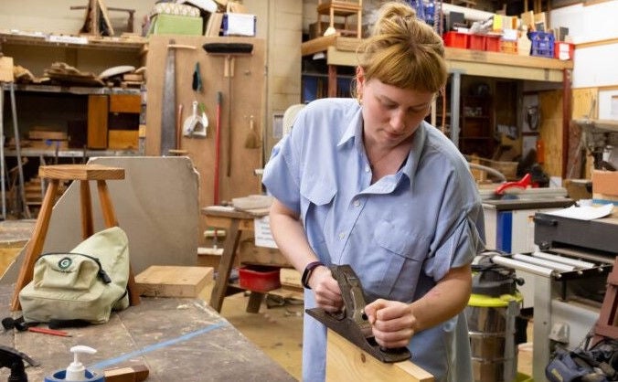 Young woman planing a piece of wood