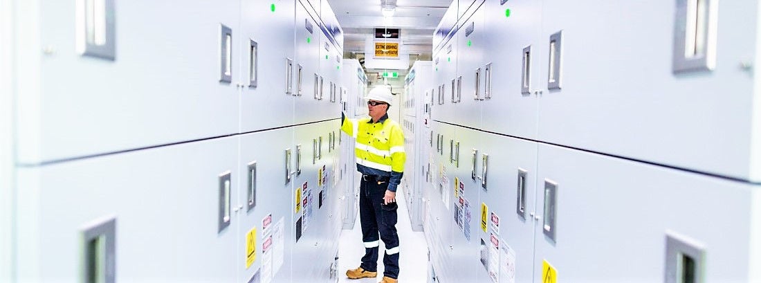 Worker in hi-vis in a corridor of batteries