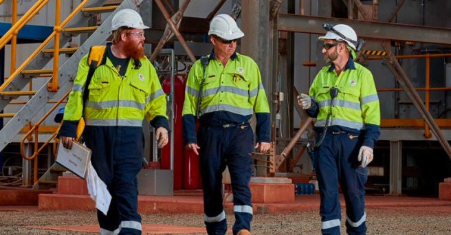 Three workers at a power generator walking towards the camera