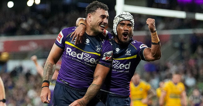 Two smiling and triumphant rugby players hugging during a game