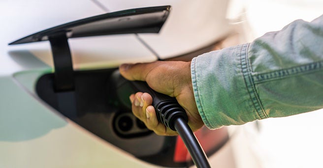 Close up of male hand plugging charger into Tesla EV