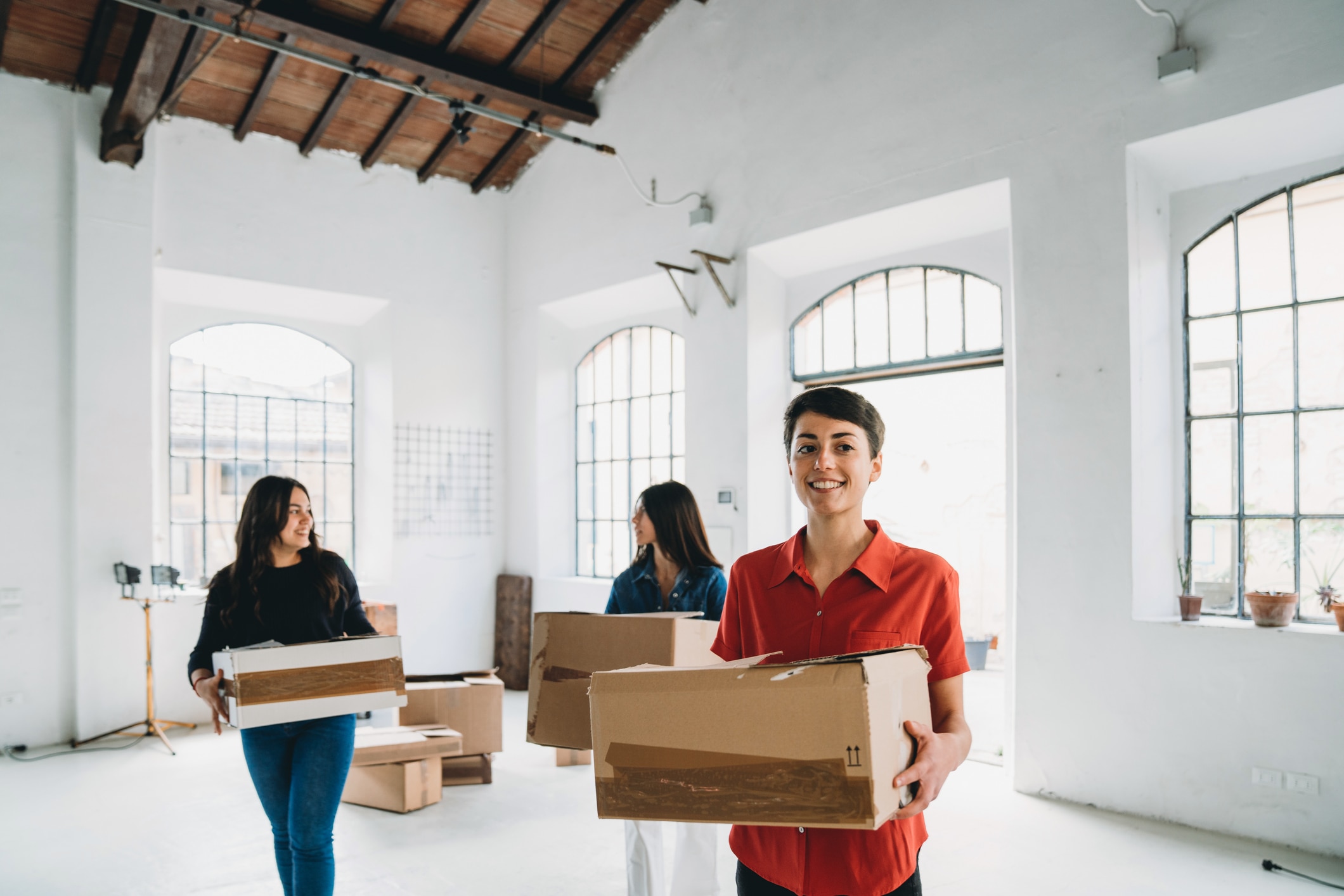 Smiling person holding a cardboard box in a light and airy room