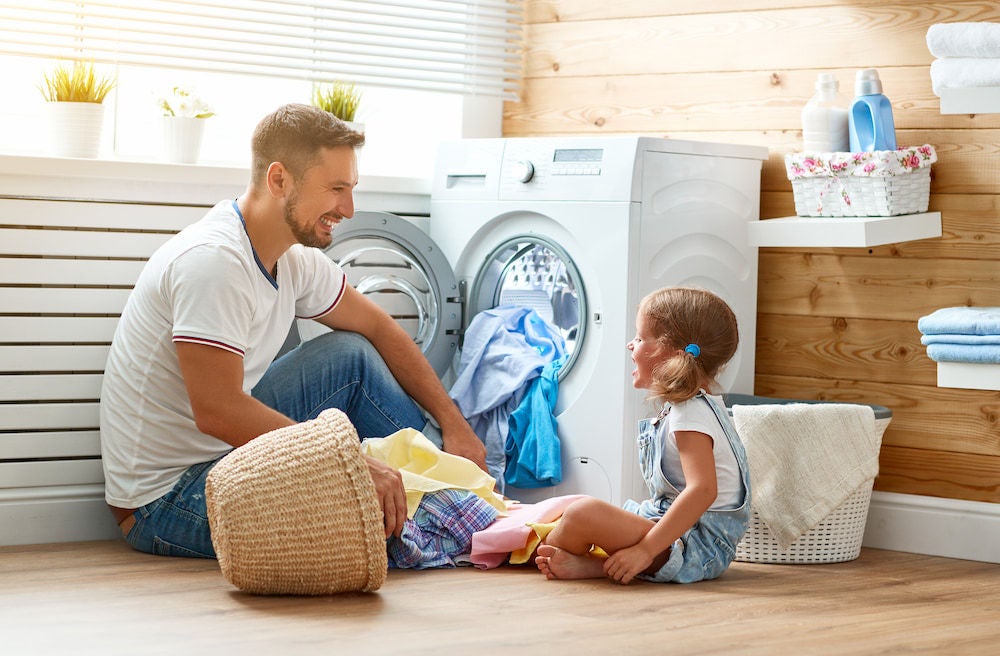 Father and daughter organising clothes into a washing machine