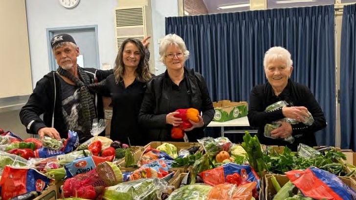 One man and three women distributing vegetables. 