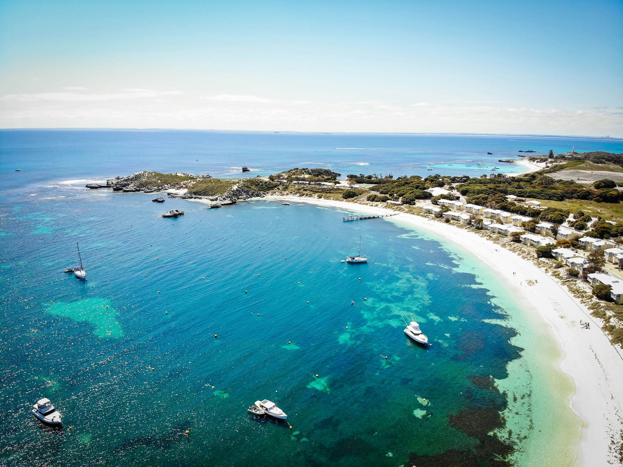 Overlooking a bay in Rottnest Island showing turquoise sea, boats, and chalets in the dunes