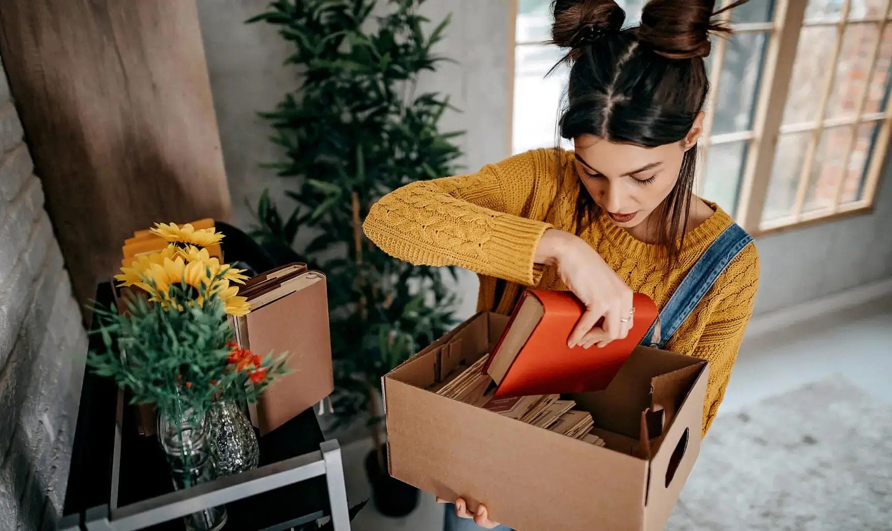 Girl holding a box of books while moving house
