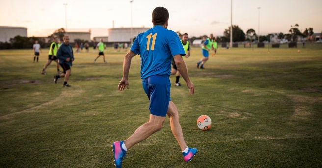 Back of man in a blue kit about to kick a soccer ball in a game of soccer