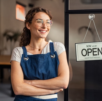 Women smiling at shop door with open sign