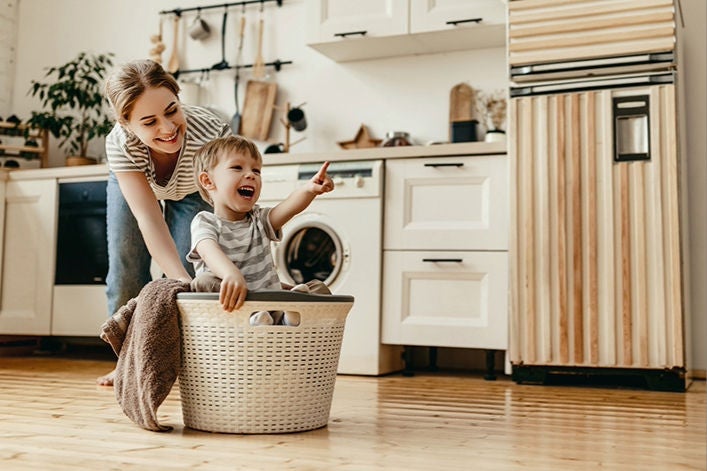 Happy family mother housewife and child son in laundry with washing machine