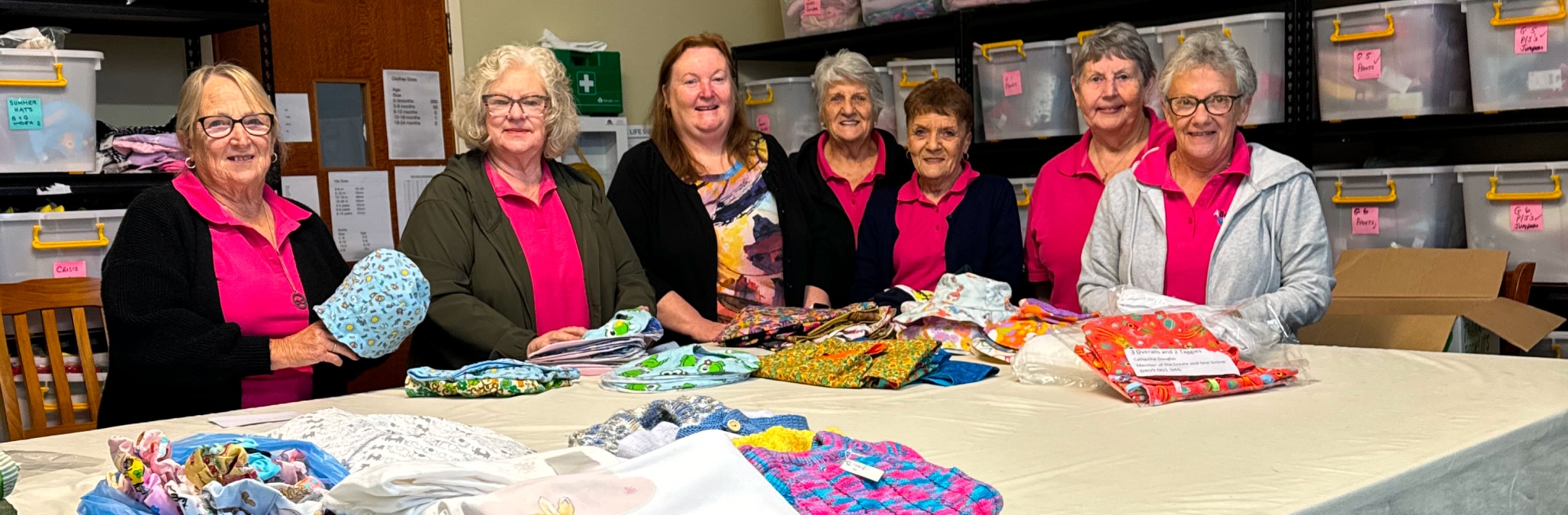 Group of smiling volunteers at A Better Life For Foster Kids with some of their handmade support items
