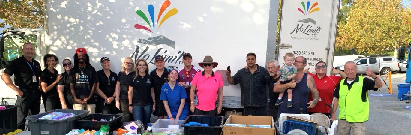 Crew of volunteers from No Limits in front of large truck displaying No Limits logo