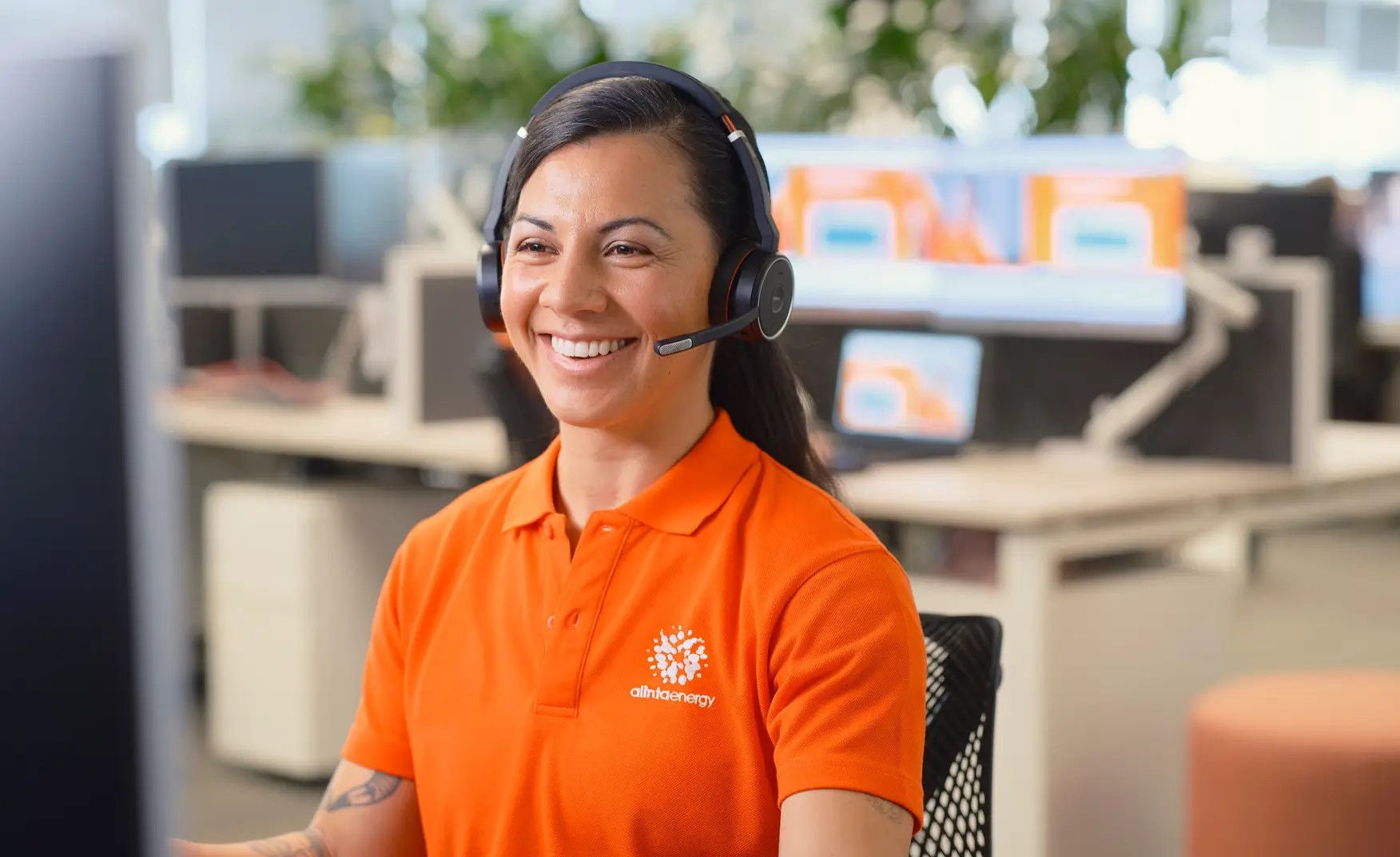 Smiling Alinta Energy staff member wearing a headset and sitting in the office