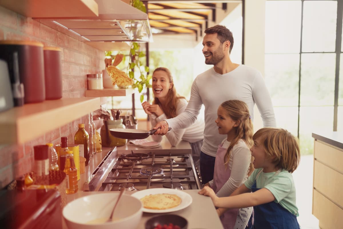 Family of four cooking pancakes and laughing