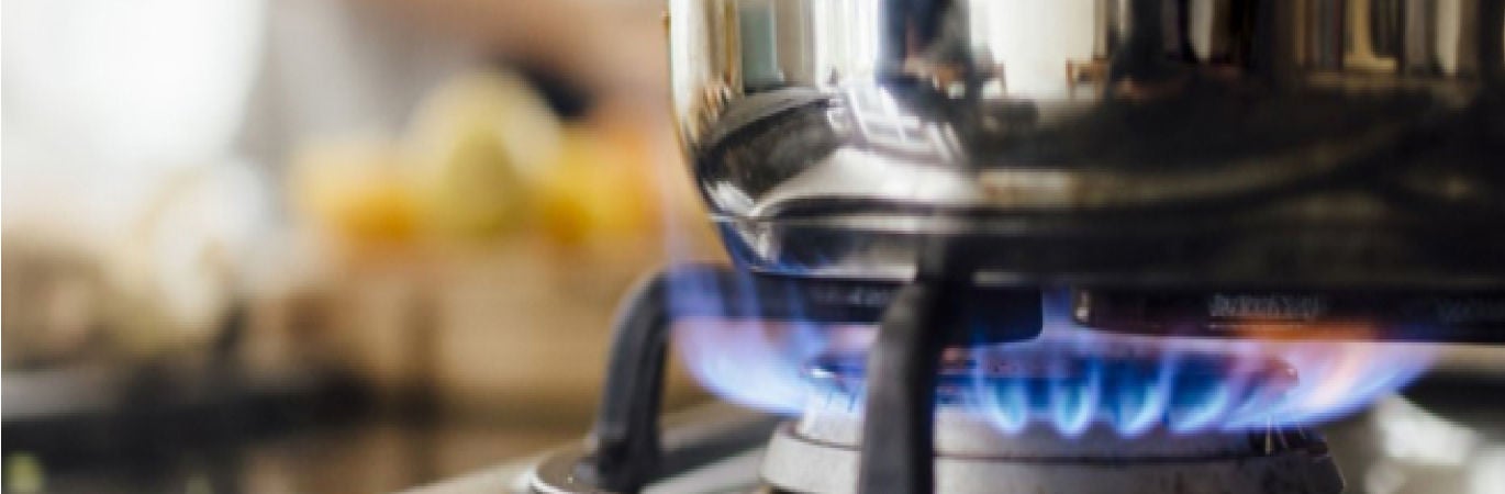 Close up of lit gas hob with saucepan