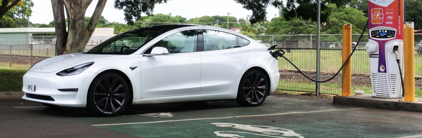 White electric car parked and plugged into a public charger