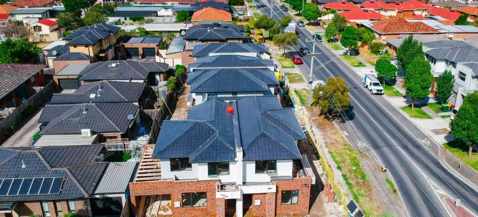 Aerial view of suburb showing roof tops of homes and a busy road to the side