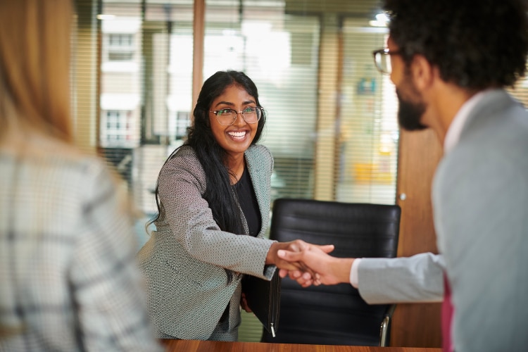 Smiling female candidate shaking hands with male interviewer in an office