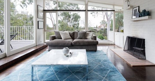 Grey sofa and blue carpet in bright airy lounge