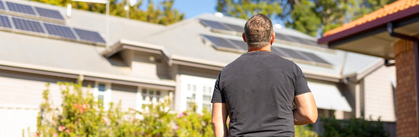 Man looking at solar panels on a roof