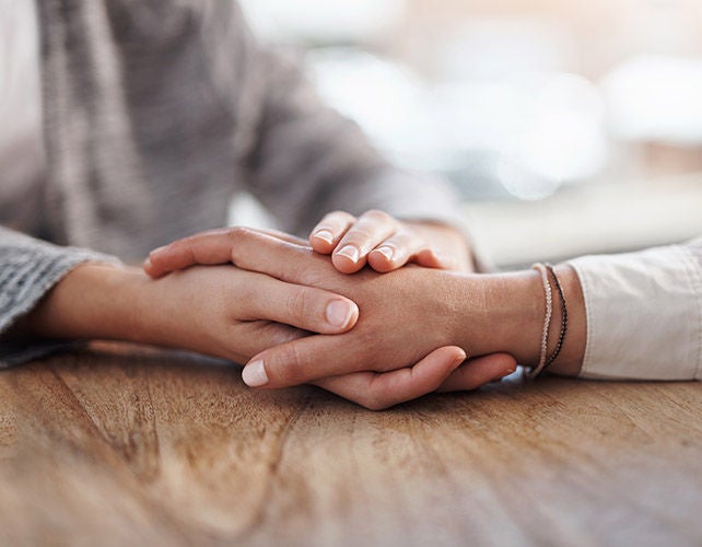 Woman's hands holding another woman's hand in empathy