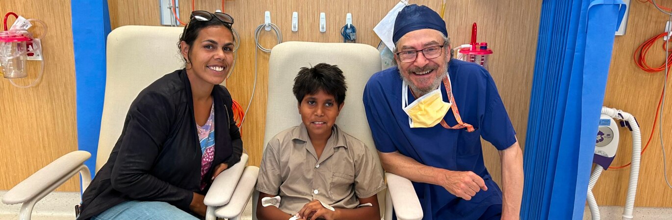 Smiling indigenous mum and son with ENT doctor in a hospital ward