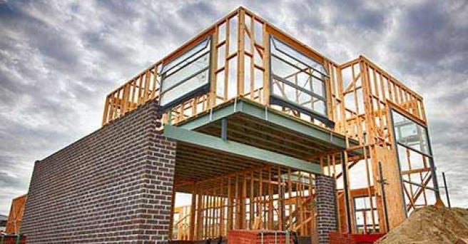 Home in early stage of being built with wooden frame and bricks