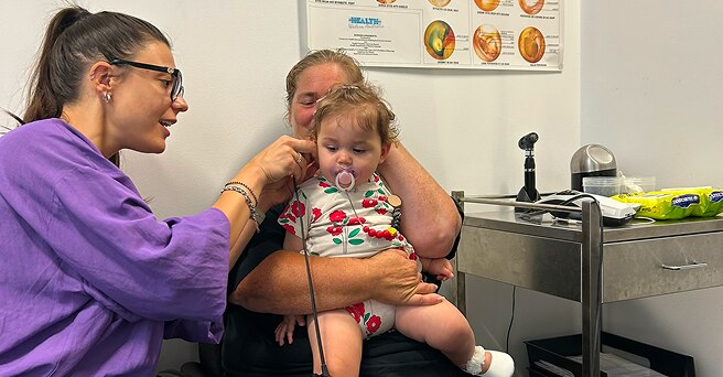 A young doctor examines a toddlers ears in a hospital setting