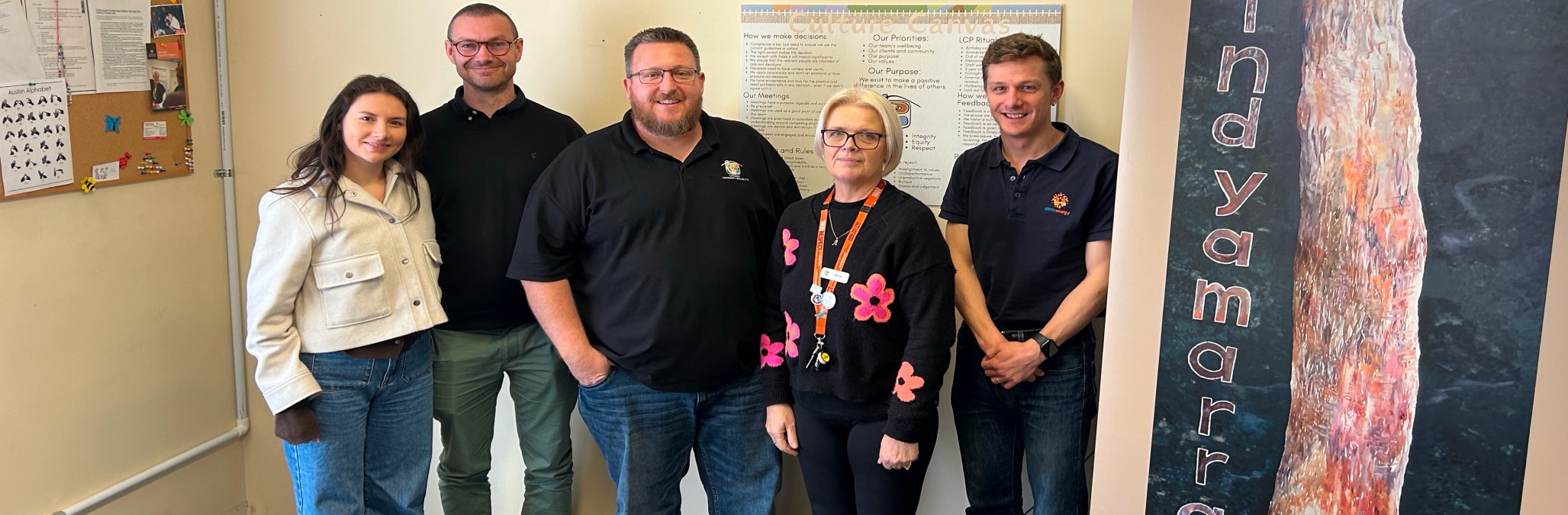 Smiling group of volunteers from Lithgow Community Projects with Alinta Energy's Darcy Wall