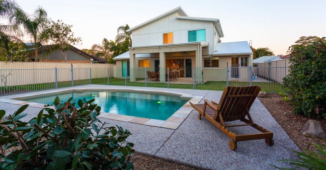 Pool lounger by pool in back garden with house in background