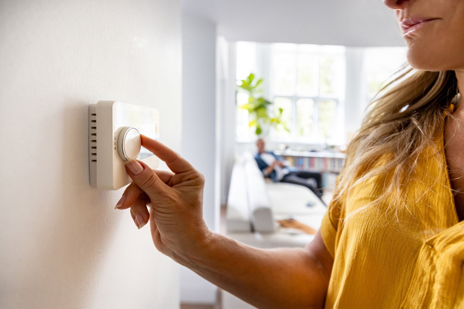 Close up of woman adjusting wall thermostat