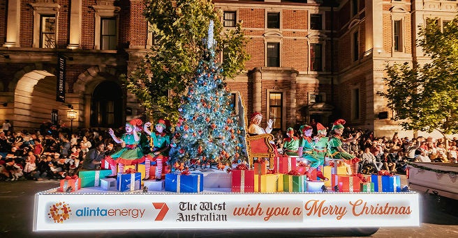 Side view of the Alinta Energy float at the Christmas Pageant showing the children dressed as elves waving to the crowd