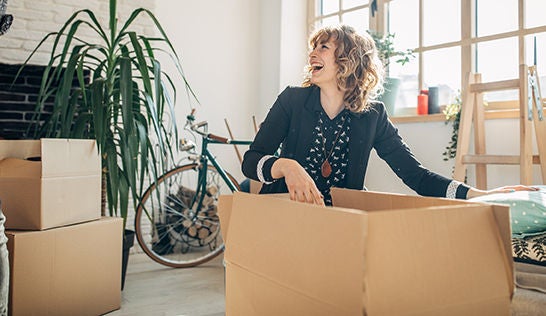 A laughing woman sitting on the floor with a large packing box