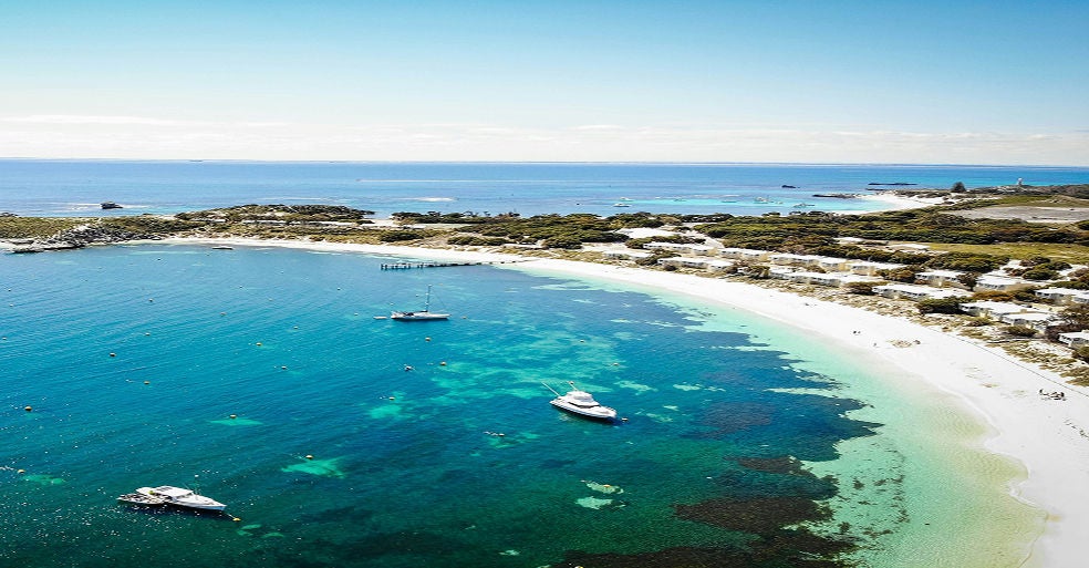 Overlooking a bay in Rottnest Island showing turquoise sea, boats and chalets on the dunes