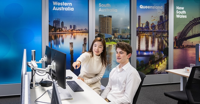 A graduate in the Alinta Energy office is being helped by a mentor at the computer