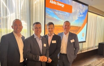 Four men in suits standing in front of presentation display